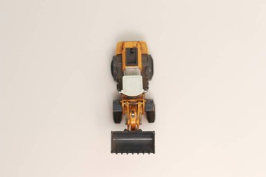 a close up of miniature orange wheel loader toy isolated on white background. concept photo of heavy equipment miniature toy.