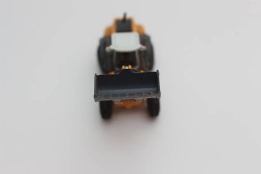 a close up of miniature orange wheel loader toy isolated on white background. concept photo of heavy equipment miniature toy.