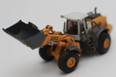 a close up of miniature orange wheel loader toy isolated on white background. concept photo of heavy equipment miniature toy.