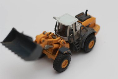 a close up of miniature orange wheel loader toy isolated on white background. concept photo of heavy equipment miniature toy.