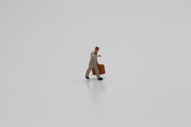 a close up of a miniature figure of an office worker carrying a suitcase isolated on a white background. Miniature figure photo concept.