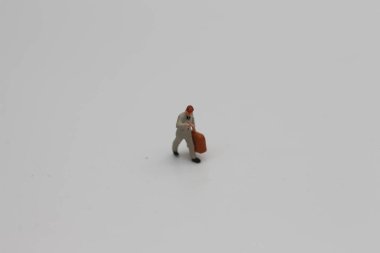 a close up of a miniature figure of an office worker carrying a suitcase isolated on a white background. Miniature figure photo concept.