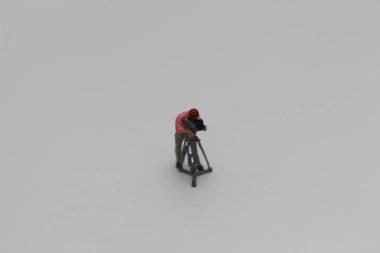 a close up of miniature figure of a videographer isolated on white background. Miniature figure photo concept.