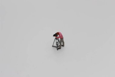 a close up of miniature figure of a videographer isolated on white background. Miniature figure photo concept.
