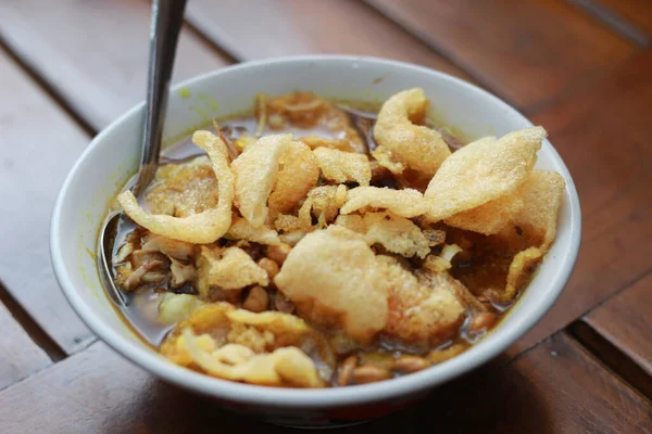 stock image a close up of a ready-to-serve bowl of chicken porridge with a natural patterned wooden background. Indonesian food concept.