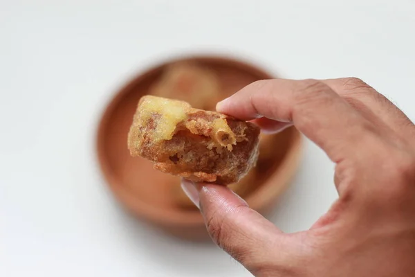 stock image a close up of fried stuffed tofu or Gorengan Tahu Isi holding in hand isolated on white background and bowl of stuffed fried tofu blurry. Indonesian food concept.