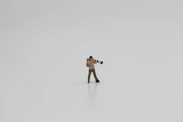 在白色背景上与照相机和心灵感应镜头隔离的摄影师的缩影 缩微胶片图片概念 — 图库照片