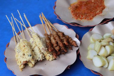 Kızarmış yumurta ve kırmızı biber soslu tavuk bağırsağıyla kaplanmış tavuk satay resmi. Sate Taichan adında bir Endonezya yemeği. Yemek konsepti fotoğrafı.