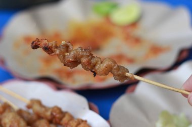photo of chicken intestine satay and served with red chili sauce. Indonesian food called Sate Taichan. Food concept photo.