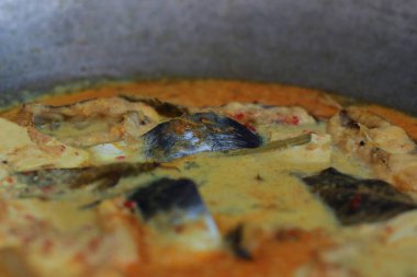 photo of tuna fish and white tofu in yellow spice sauce on a frying pan. Indonesian traditional food photo concept.