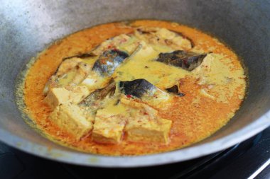 photo of tuna fish and white tofu in yellow spice sauce on a frying pan. Indonesian traditional food photo concept.