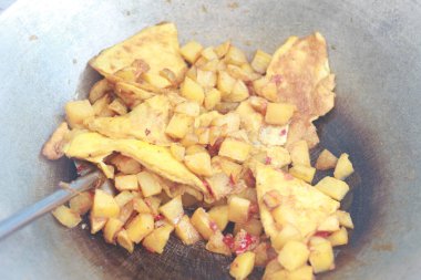 photo of cooking potatoes and omelet with spicy seasoning or balado on a frying pan. concept photo of Indonesian food.