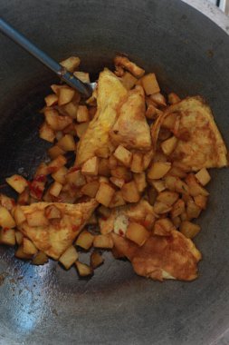 photo of cooking potatoes and omelet with spicy seasoning or balado on a frying pan. concept photo of Indonesian food.