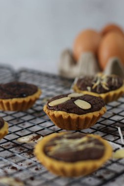 Small chocolate pie with almonds topping served on a cake rack, tastes sweet and savory. Food concept photo.