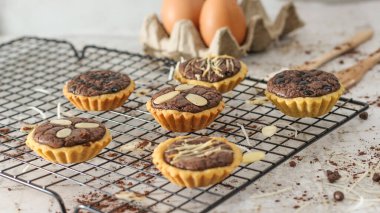 Small chocolate pie with almonds topping served on a cake rack, tastes sweet and savory. Food concept photo.