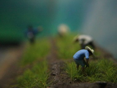 a close up of miniature figures of farmers planting rice. Farming photo concept.