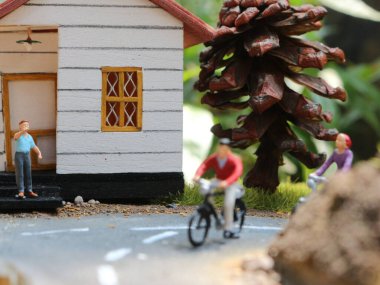 a close up of a miniature figure of a cyclist greeting other people. social photo concept.