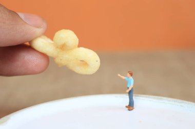 miniature figure of a child interacting with human hands giving food.