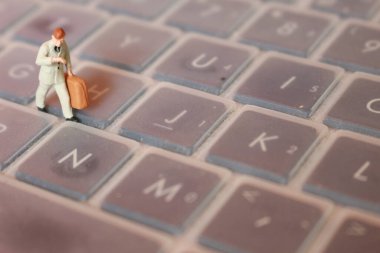 a miniature figure of an office worker carrying a briefcase walking between the keyboards.