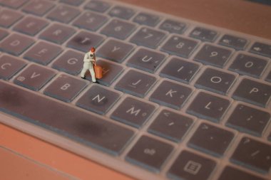 a miniature figure of an office worker carrying a briefcase walking between the keyboards.