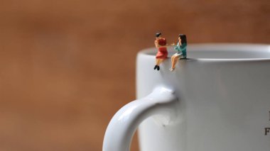 Miniature figures of 2 women talking over glasses. discussion concept.