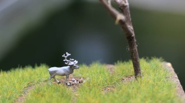 miniature figure of a moose eating. a meadow and tree diorama. concept of nature and animals.