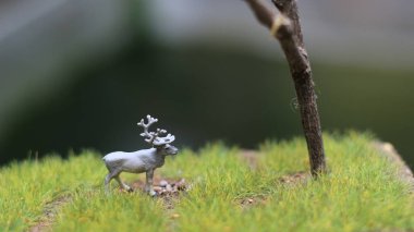 miniature figure of a moose eating. a meadow and tree diorama. concept of nature and animals.