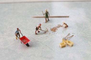 miniature figures of workers working together to move grain.