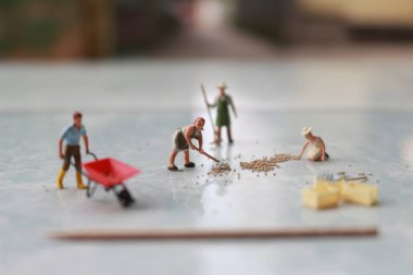 miniature figures of workers working together to move grain.
