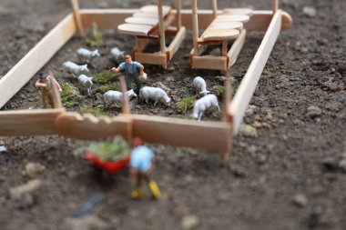 A close up of miniature figure of a goat herder feeding in a wooden cage. Shepherd concept.