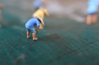 miniature figures of farmers working on a cutting mat. concept of agriculture photo.