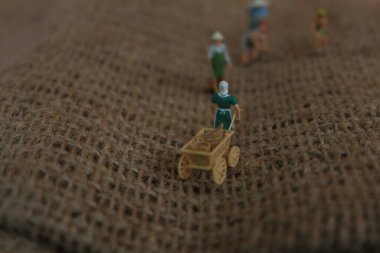 miniature figures of farmers working on gunny sacks. concept of agriculture photo.
