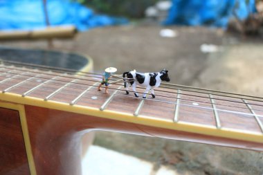 miniature figure of a farmer plowing a field with his cow on a guitar.