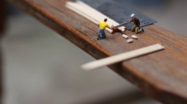 Miniature figure of a worker cutting toothpicks. carpenter activity photo concept.