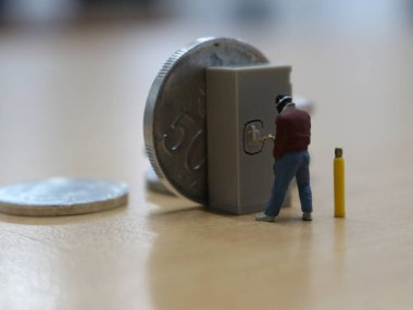 miniature figure of a robber who is trying to break into a safe of money.