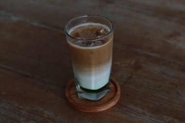 a glass of pandan coffee latte served cold on the table.