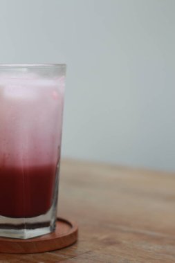 a glass of red velvet latte served cold on the table.