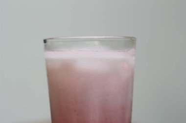 a glass of red velvet latte served cold on the table.