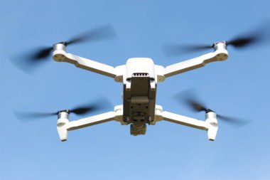 a photo of a drone flying with a blurry propeller against a blue sky background. technology photo concept.
