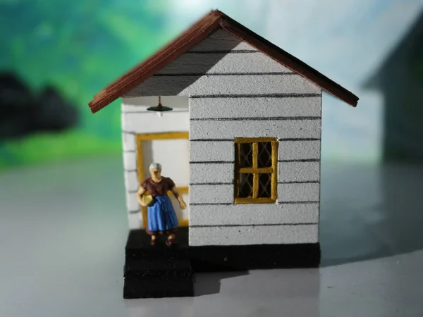 a close up of a miniature figure of a mother in front of a house. simple home photo concept.