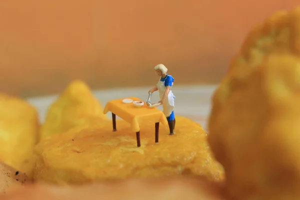 miniature figure of a mother cooking on yellow tofu.