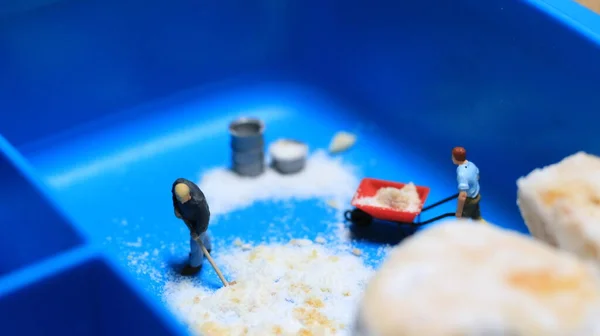 a miniature figure of a worker tidying a peanut cake sprinkled with powdered white sugar. concept of workers in the food industry.