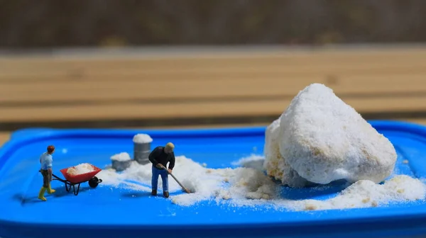 a miniature figure of a worker tidying a peanut cake sprinkled with powdered white sugar. concept of workers in the food industry.