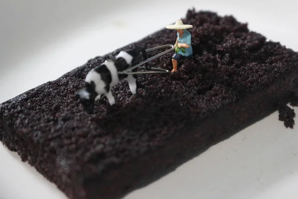 Miniature Figure Farmer Plowing Chocolate Sponge Cake — Fotografia de Stock