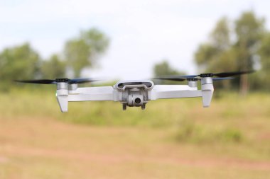 a photo of a drone flying with a blurry propeller against a green open space background. technology photo concept.