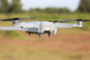 a photo of a drone flying with a blurry propeller against a green open space background. technology photo concept.