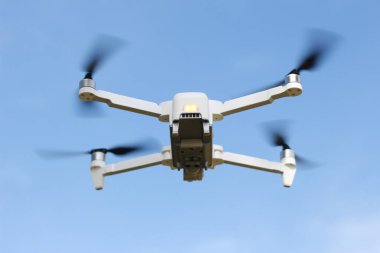 a photo of a drone flying with a blurry propeller against a blue sky background. technology photo concept.