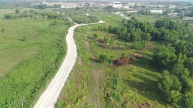 4K footage aerial view of the highway leading to residential areas between green fields.