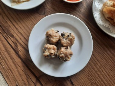 Dim sum, soslu beyaz bir tabakta sıcak servis edilir. izole edilmiş beyaz arkaplan.