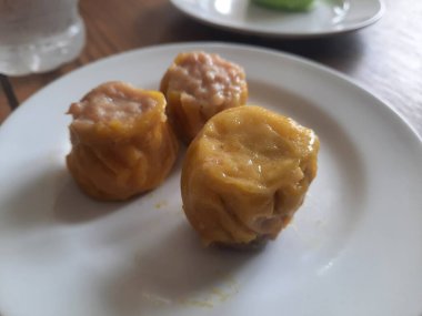 Dim sum, soslu beyaz bir tabakta sıcak servis edilir. izole edilmiş beyaz arkaplan.